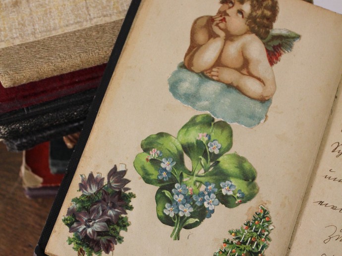 Bunte Aufkleber in einem Buch us den 1920er Jahren, zu sehen sind unter anderem ein Engel und ein Weihnachtsbaum. (vergrößerte Bildansicht wird geöffnet)