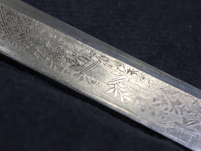 Detailaufnahme der Klingenätzung, zu sehen ist Trophäenschmuck (vergrößerte Bildansicht wird geöffnet)