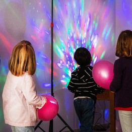 Bilder von Kindern in einem Raum, der durch buntes Neonlicht beleuchtet ist.